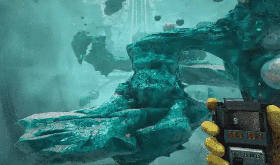 A first-person view of a person holding a digital device with a screen in a green, alien-like environment with rocky formations and floating objects.